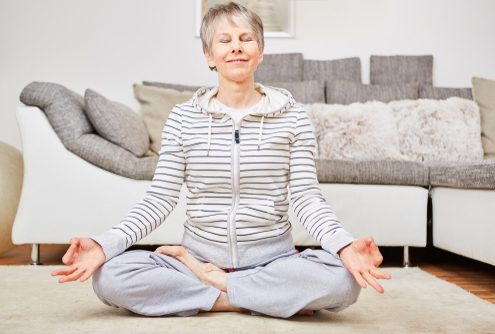 older woman doing yoga at home