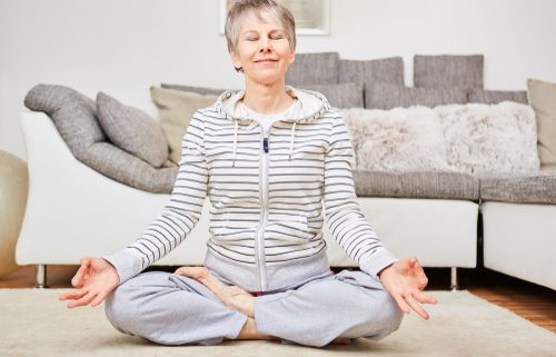 older woman doing yoga at home