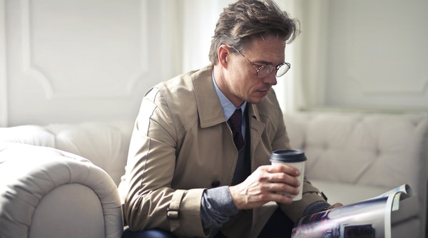 man reading a magazine drinking coffee - how long does oxycodone stay in your system