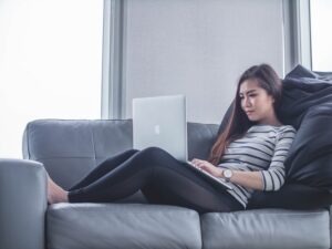 woman sitting on grey couch with macbook researching iv infusion at home in los angeles