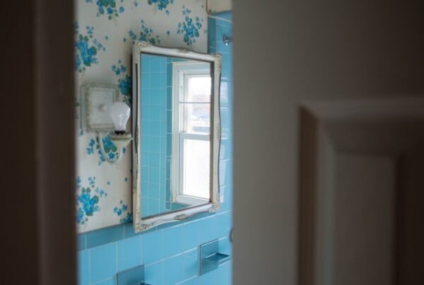 image of blue tile bathroom with blue and white wall paper with mirror on the wall as if looking into a bathroom from the door for article bathroom safety for the elderly